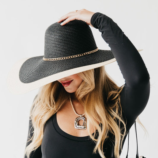Two-tone wide floppy sun hat, black crown with tan brim and gold chain band, worn