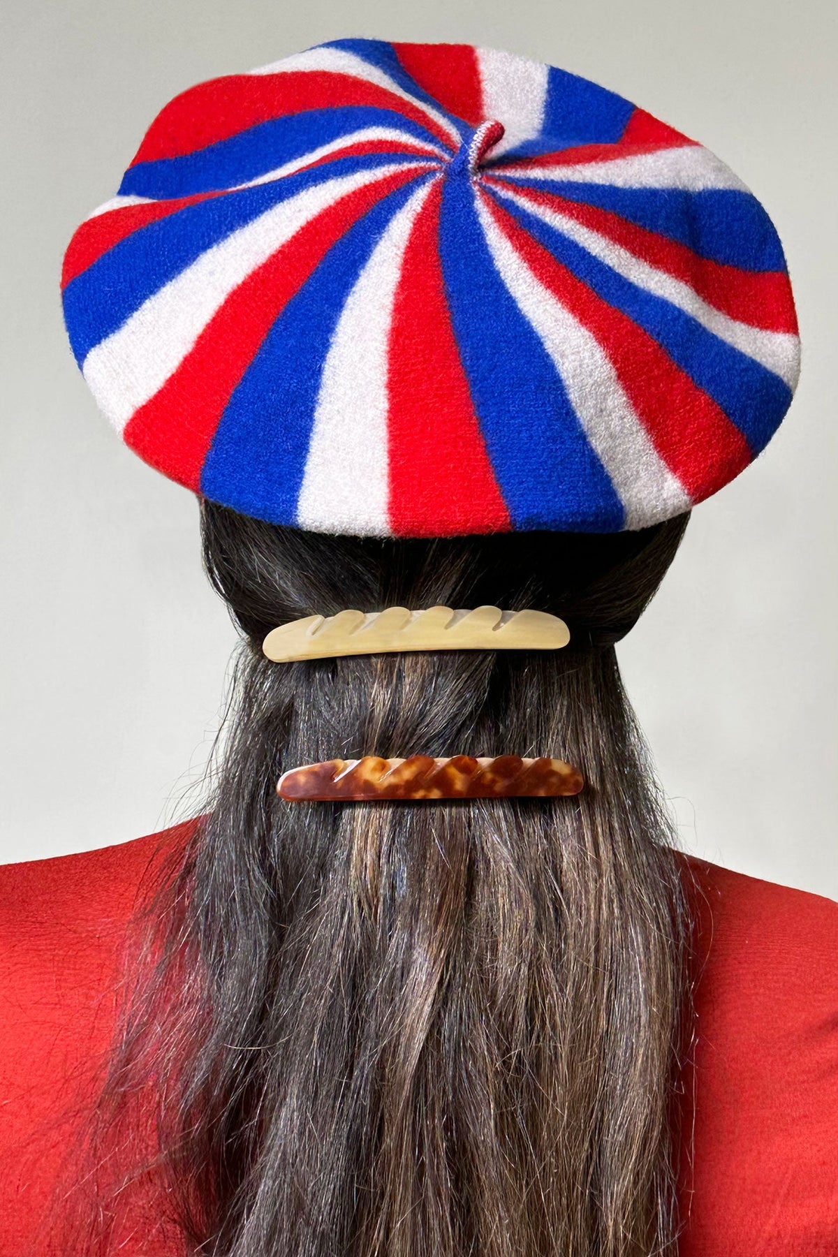 Cream baguette hair barrette on dark hair under a red white blue beret