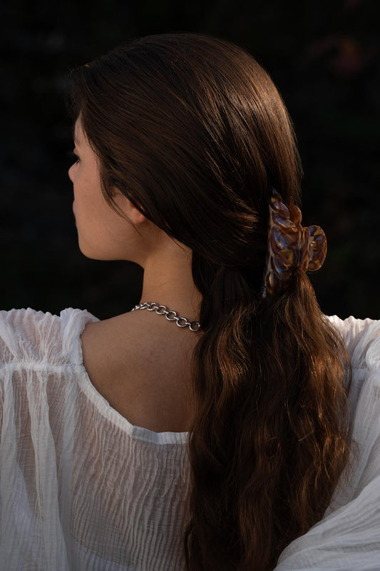 Croissant hair claw clip with marbled stones on long brown hair, side view