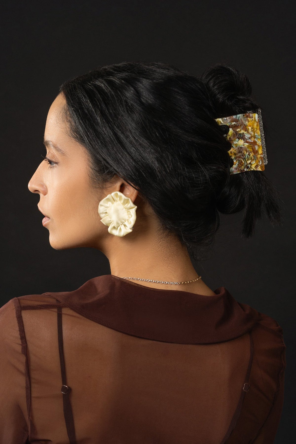 Decorative hair claw worn in dark hair, gold glitter resin design with curved prongs