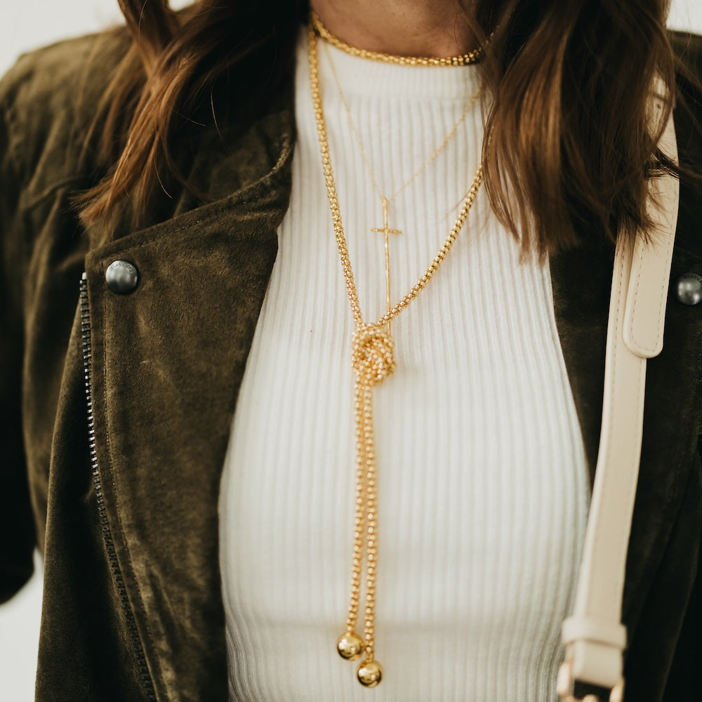 Gold-tone layered chain choker necklace with textured pendant and small cross charm