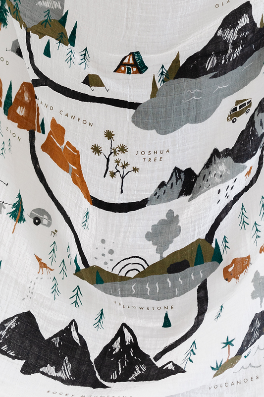 Baby swaddle blanket close-up, white with mountains, trees and hiking-route map print