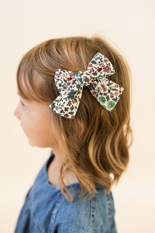 Petite hair bow on blonde hair; cream floral print with leafy accents