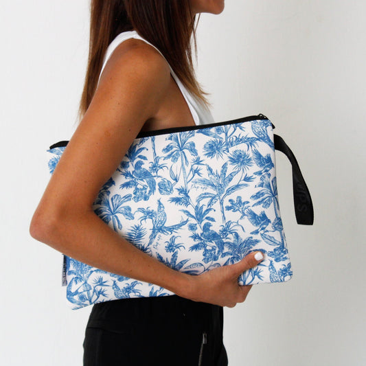 Toile laptop sleeve in blue and white floral pattern, carried by the handle
