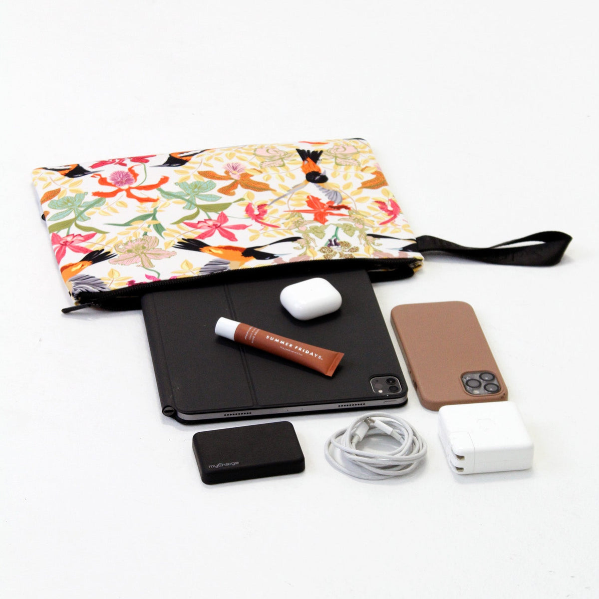 Tropical laptop sleeve with black zipper, shown with phone and small accessories