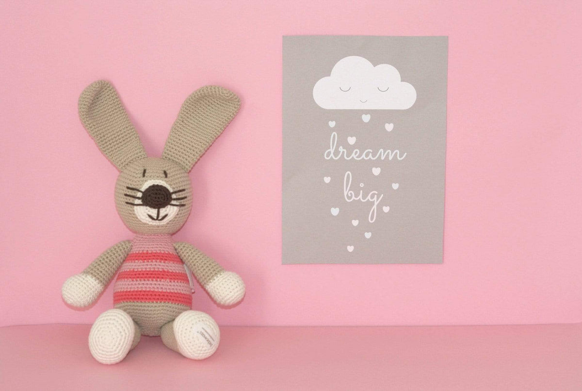 Crocheted rabbit plush with long ears, white paws, and a pink striped shirt