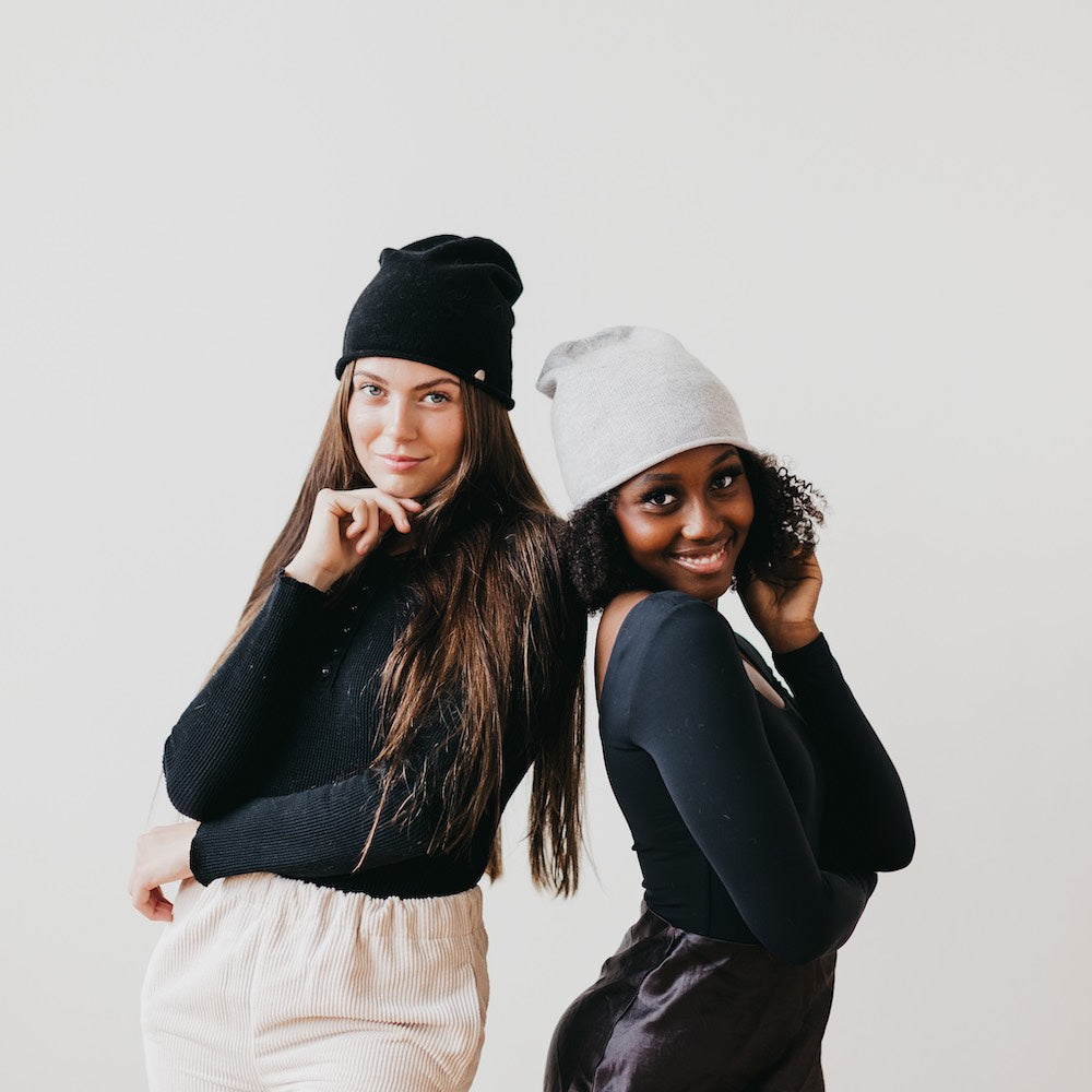 Black and light gray rolled-edge cashmere beanies shown on two models