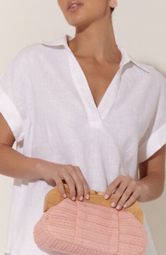 Pink woven frame clutch purse with timber handle, worn by model