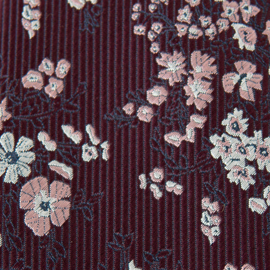 Men's floral tie close-up, burgundy striped weave with light pink and white blossoms