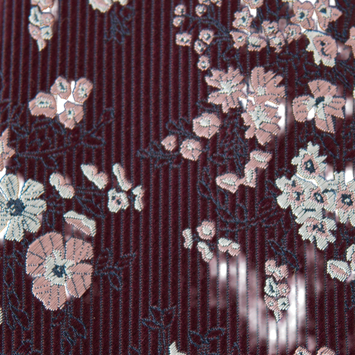 Close-up of youth necktie fabric: burgundy pinstripes with white floral motifs