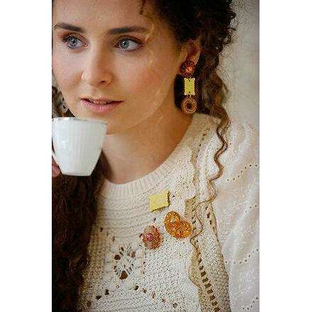 Yellow dotted square and orange flower cookie brooches on cream knit sweater