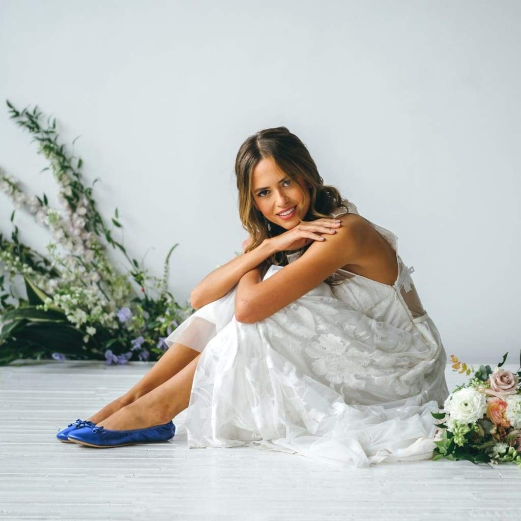 Cobalt blue metallic flats on feet, lace-up bow detail