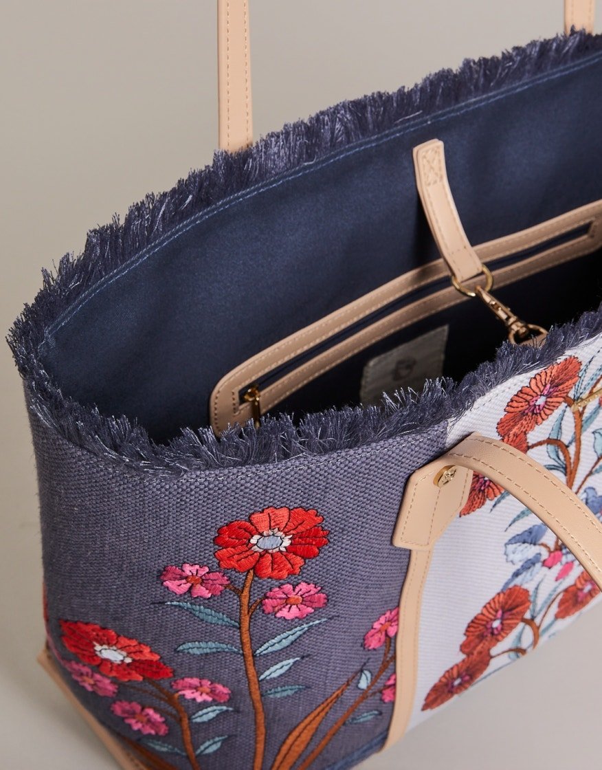 Navy embroidered tote interior with tan handles and zipped pocket plus floral side panel