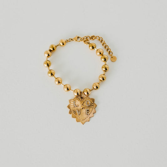Gold-tone beaded bracelet with dangling sunburst heart pendant