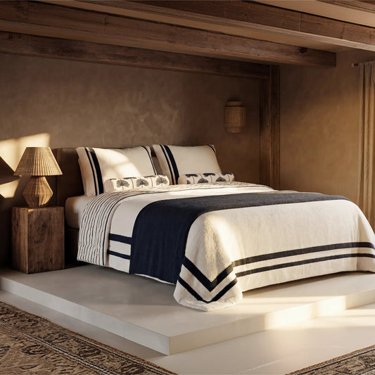 Plush comforter with navy-and-off-white striped border on a bed