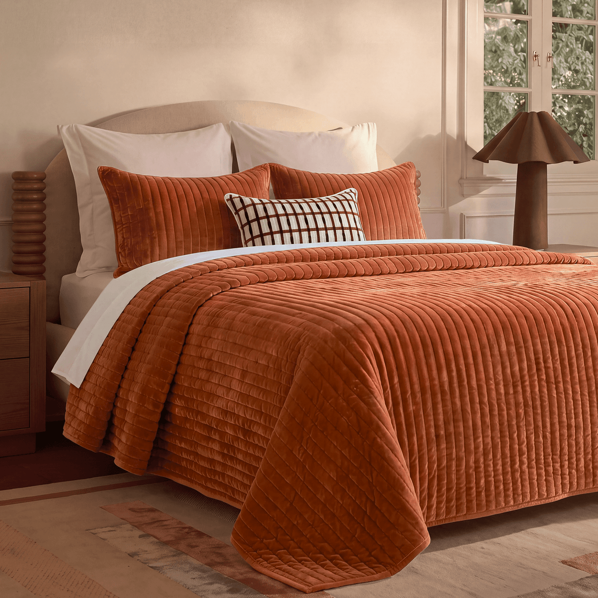 Rust-orange velvet channel quilt on bed, raised stripes and quilted edge piping