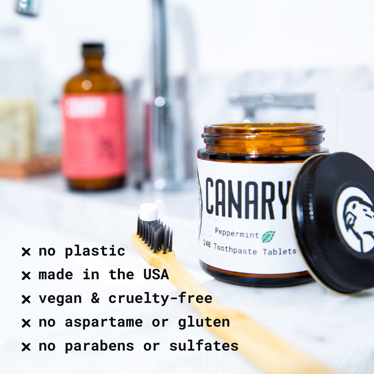 Canary peppermint toothpaste tablet jar beside a toothbrush