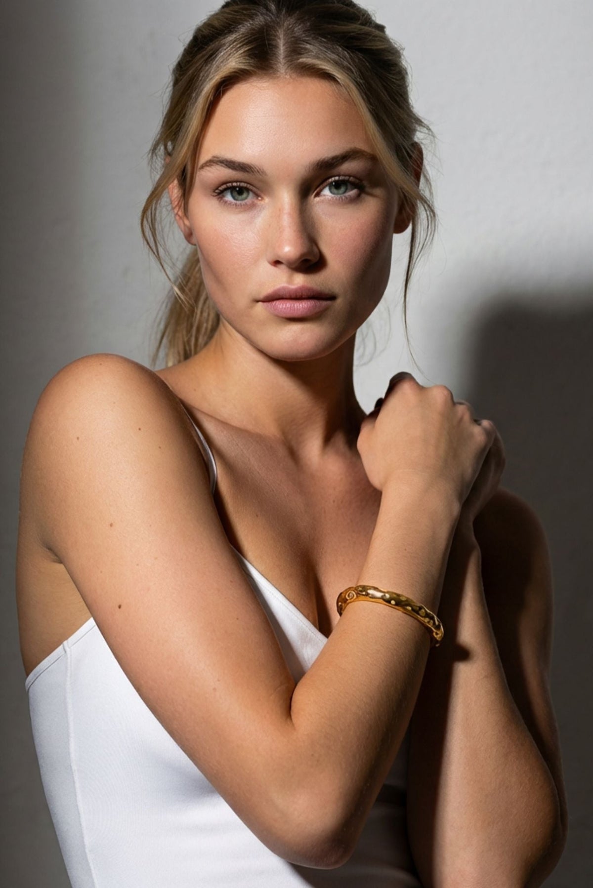 Gold textured cuff bracelet on model’s wrist, close-up