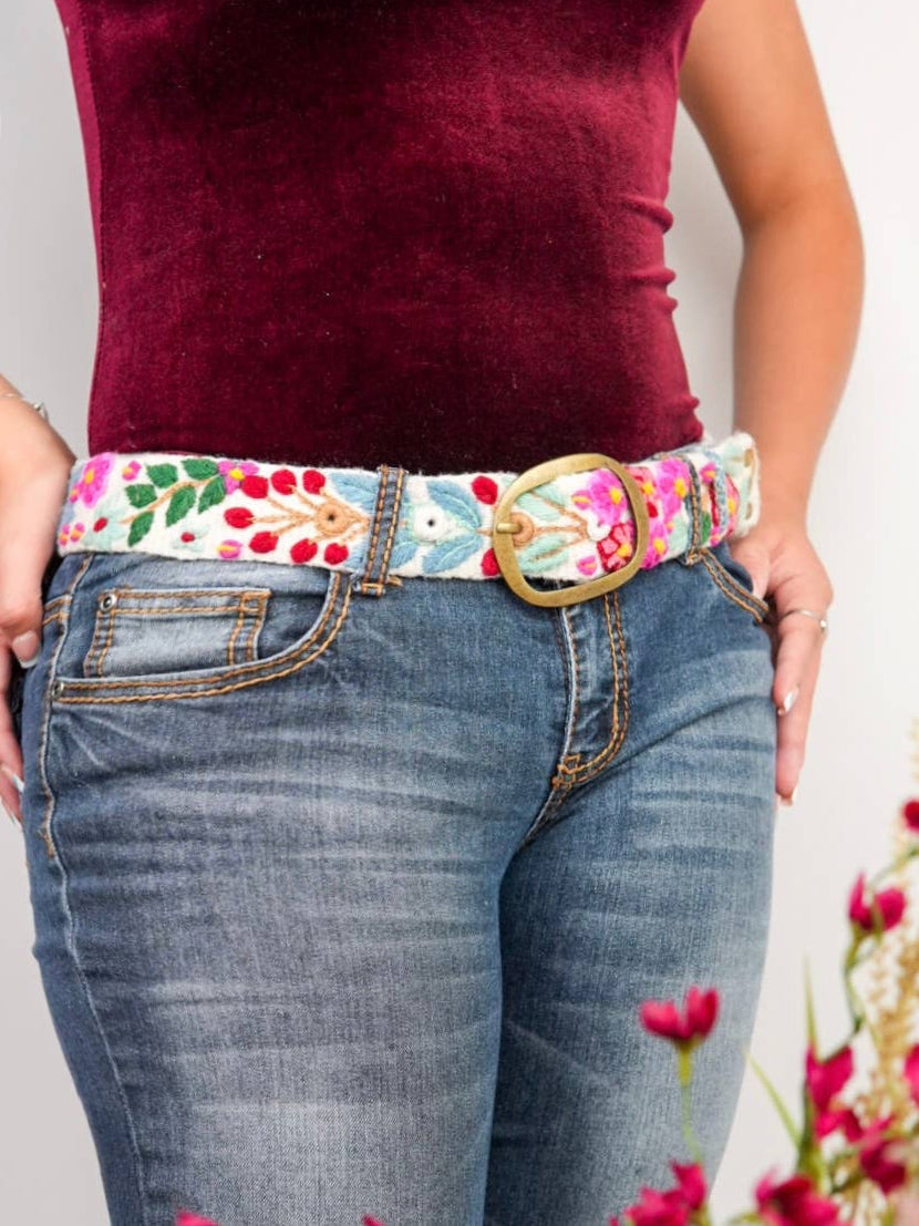Cream embroidered wide belt with multicolor floral trim and brass buckle on jeans