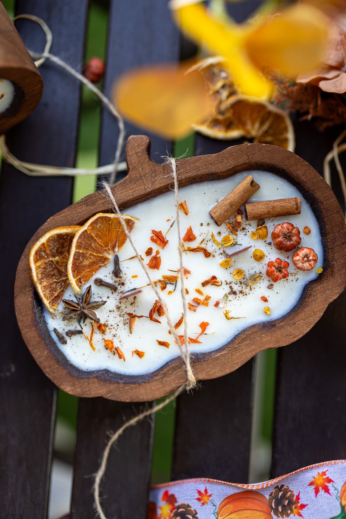 Wooden pumpkin-shaped dough bowl candle with cinnamon sticks and dried spice pieces in wax