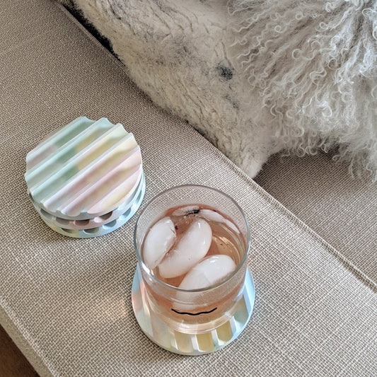 Pastel ridged coaster holding a glass of ice water on a textured surface