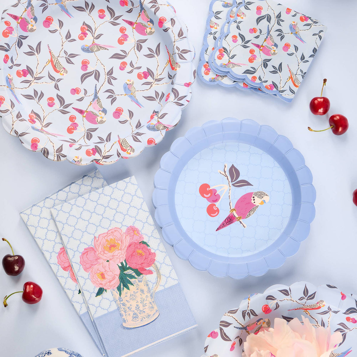 Scalloped blue dessert plate with bird and cherry illustration, top view