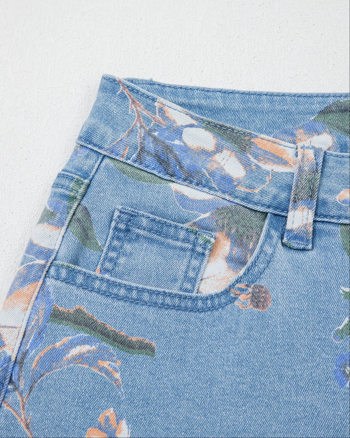Light blue denim jeans close-up with floral print and front pocket stitching
