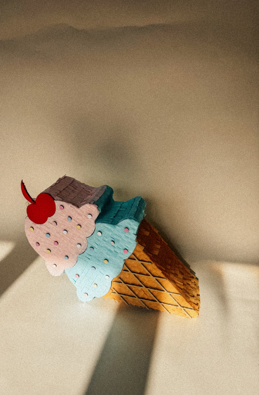 Ice cream cone piñata with pink and blue scoops, cherry, and waffle cone