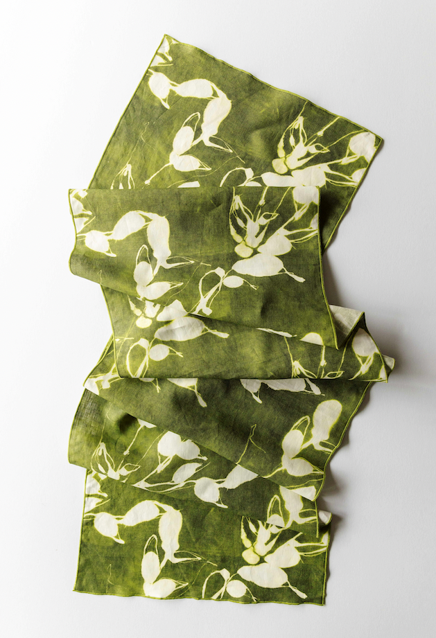 Olive green table runner with white botanical print, folded layers shown