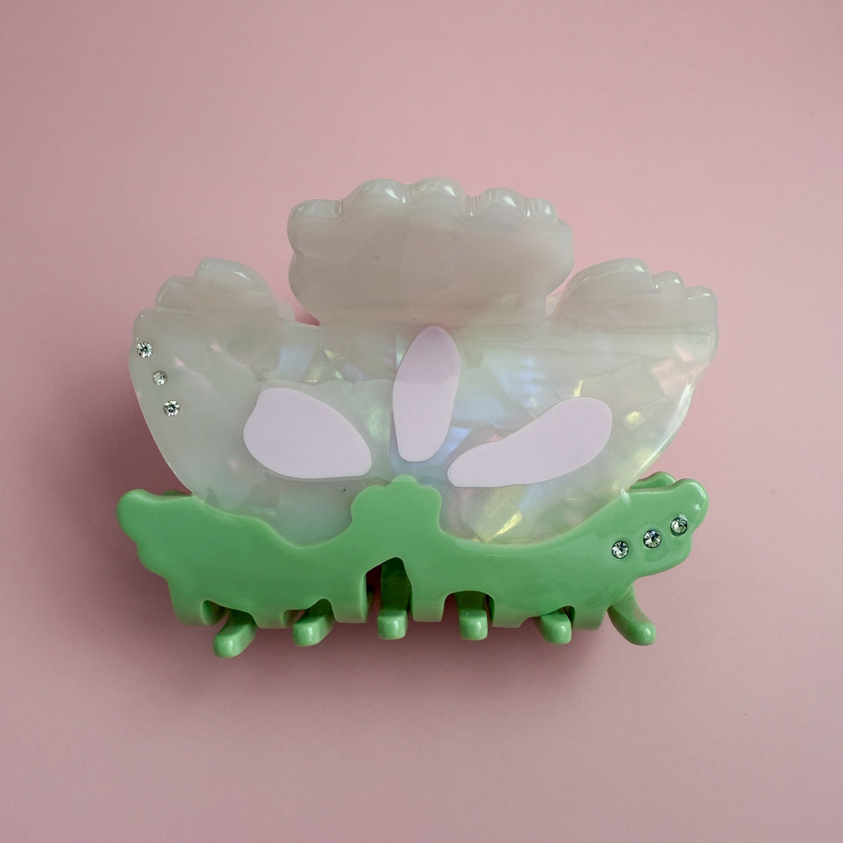 Opalescent floral hair claw with green clip teeth and lavender petal design, rhinestones