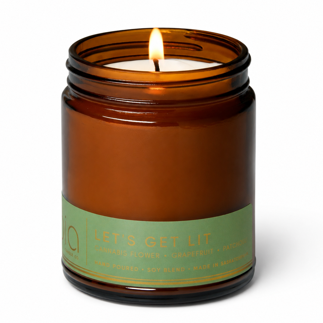 Amber glass jar candle with lit flame and green label band