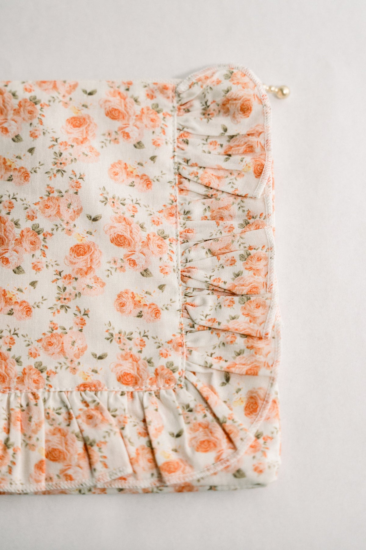 Floral ruffle zipper pouch with coral blooms; visible zipper and ruched side detail