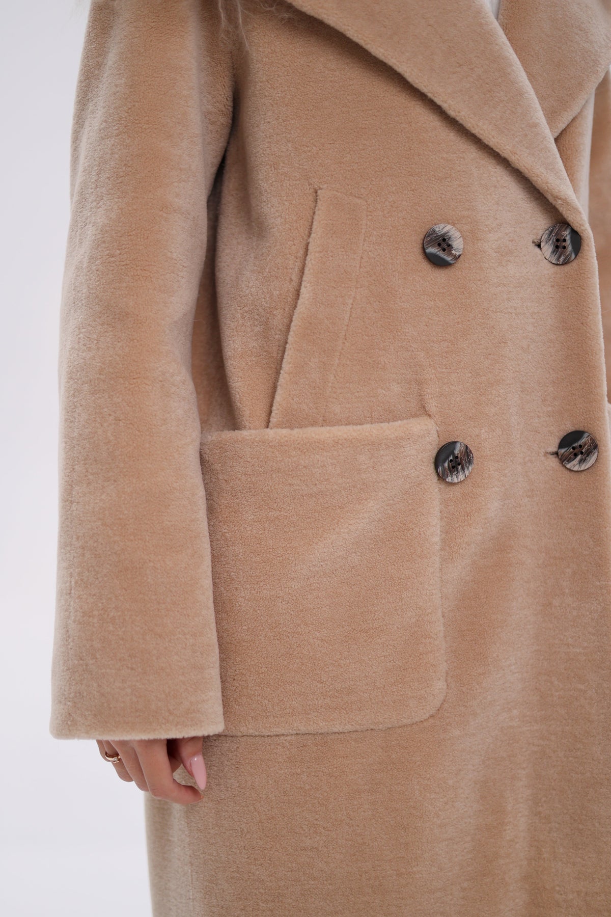 Close-up of the coat's sleeve, double-breasted buttons, and patch pocket