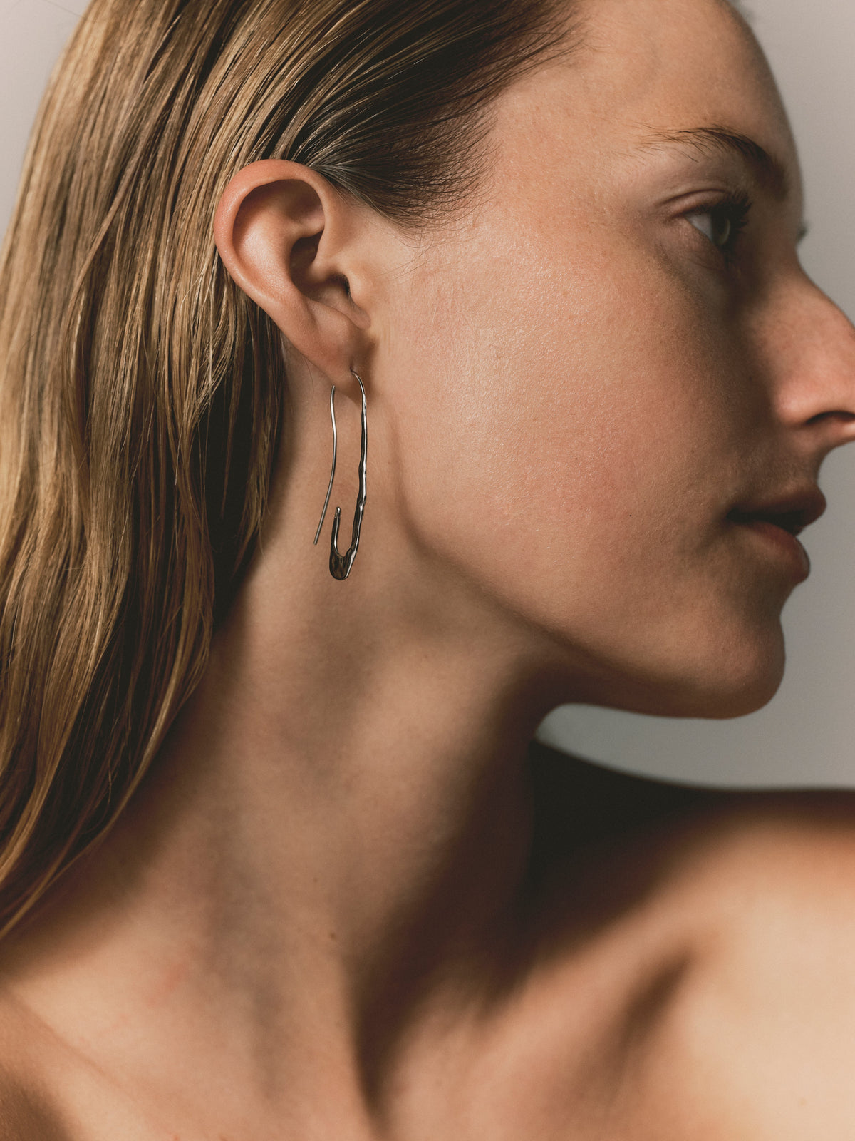 Silver paperclip earrings with hook back, elongated wavy drop visible in profile