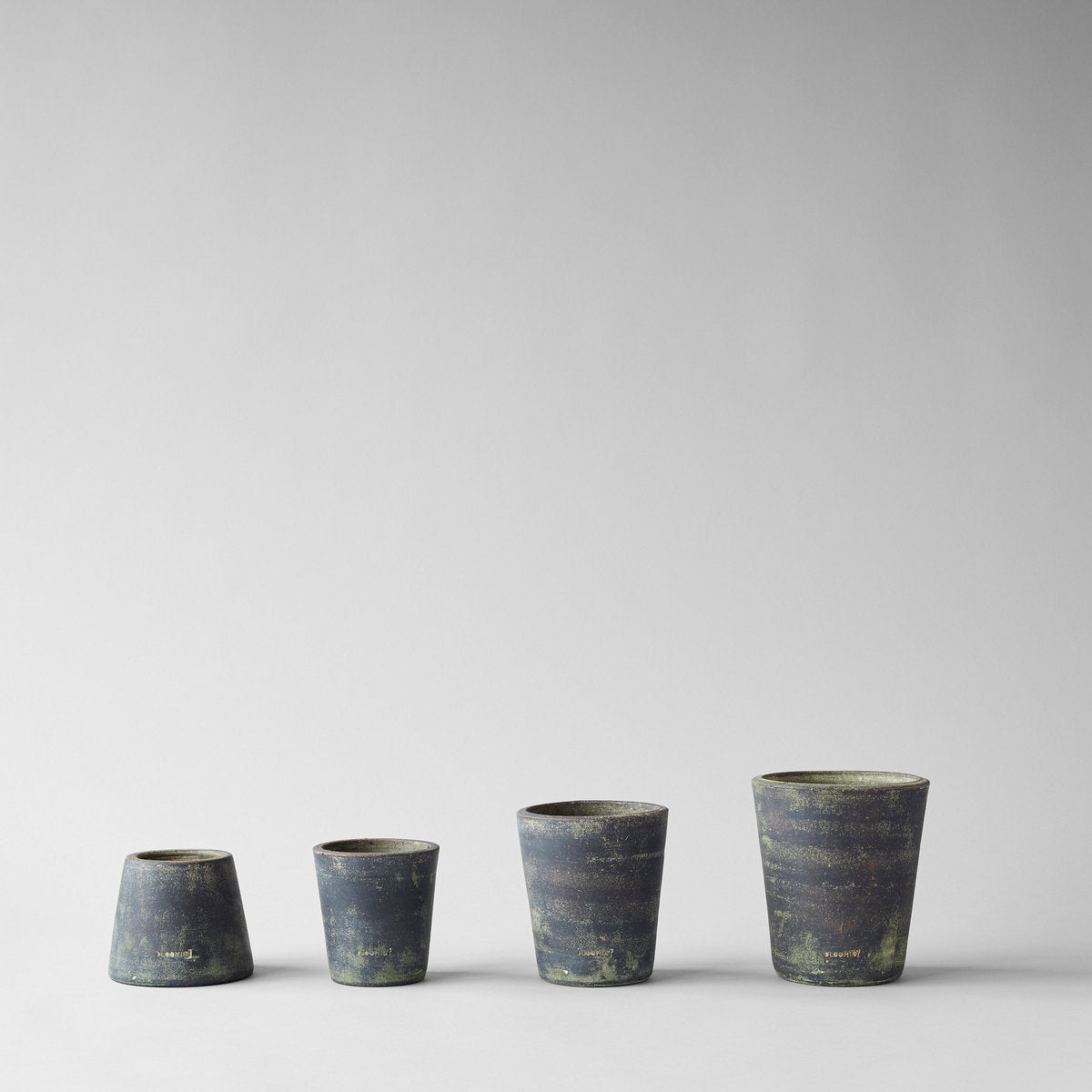 Grey patina terra cotta planters, four pots in a row, tapered cylinder shapes