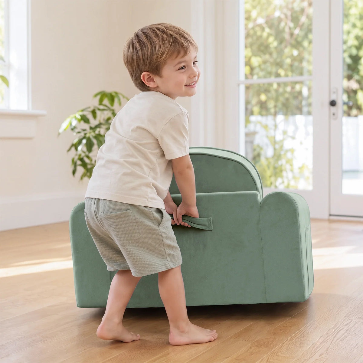 Tiny Land® light green kids sofa with a child carrying it by the side handle.