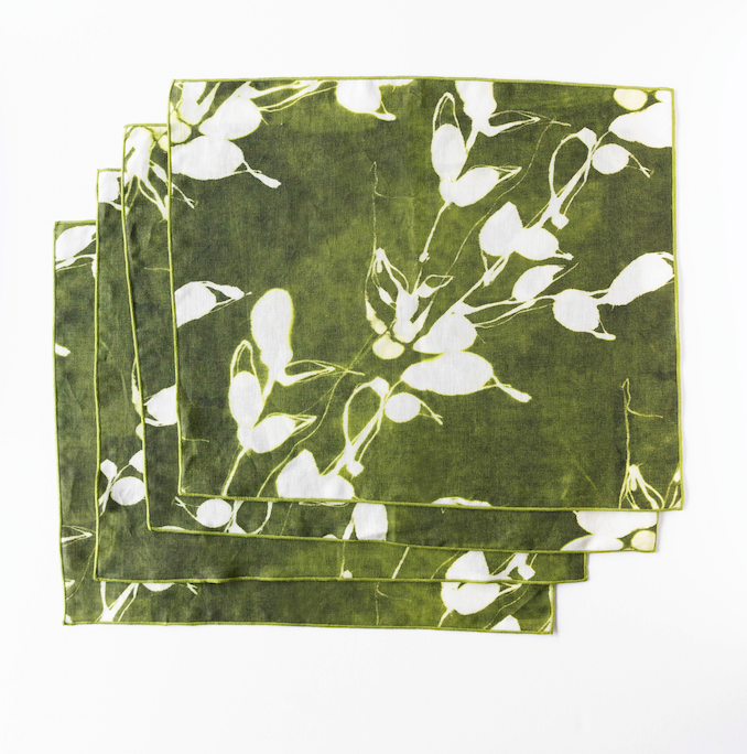 Stacked olive green placemats with white floral vine print, overlapping edges