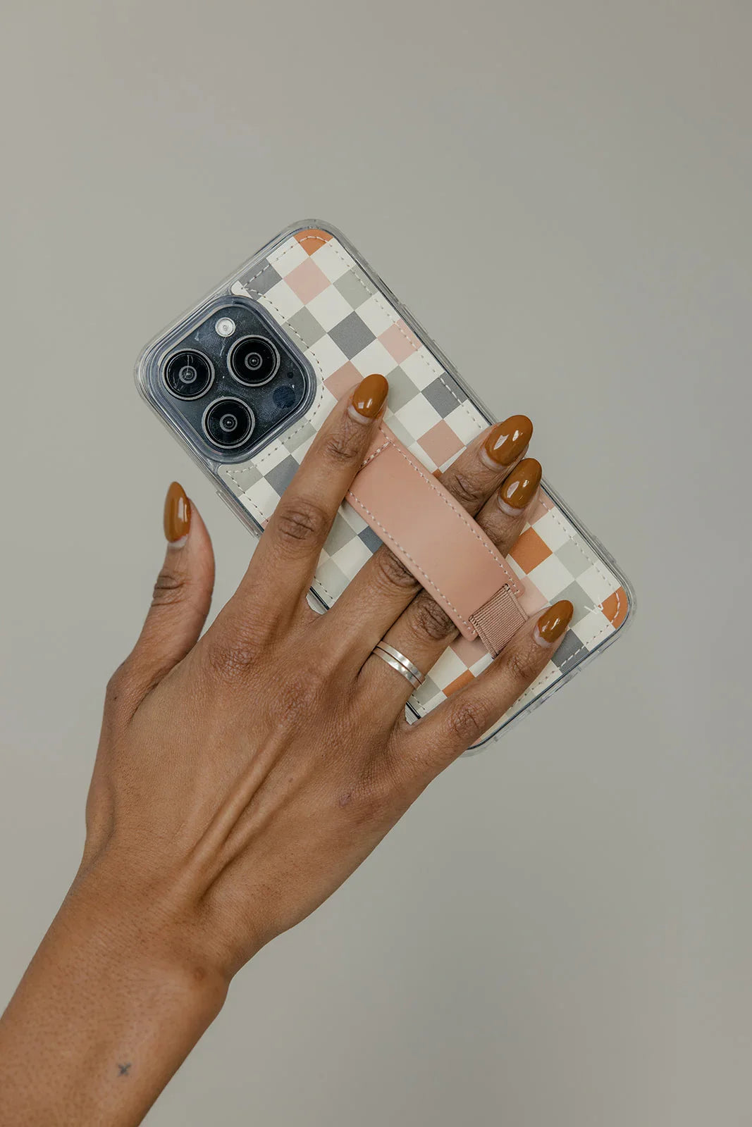Clear check pattern phone case with tan strap, held with fingers