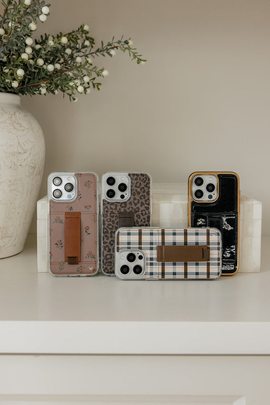 Assorted phone cases including Mauve Meadow floral case on a display stand