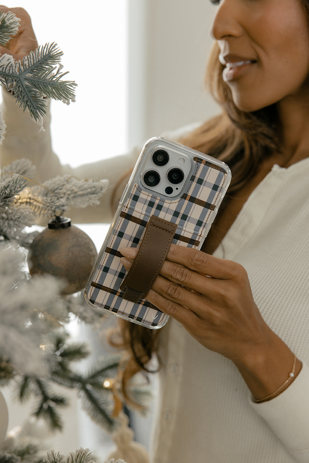 Plaid phone case with brown leather strap on a phone in hand