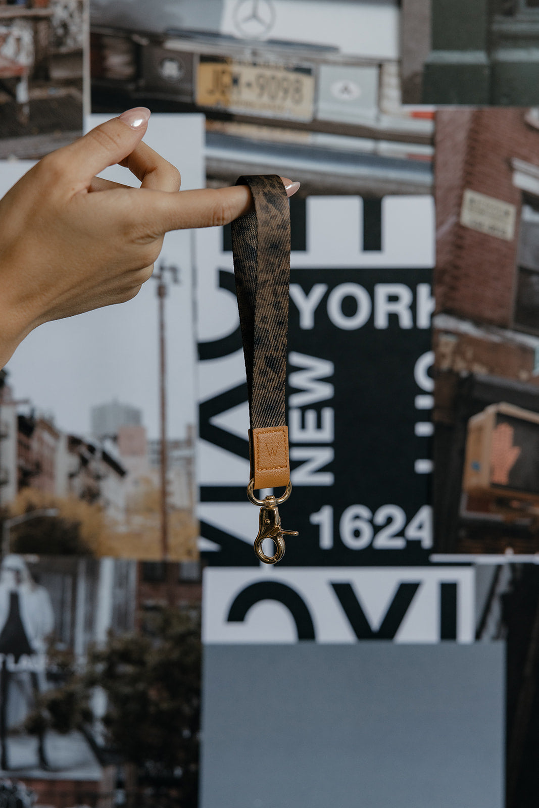 Brown wrist lanyard hanging from a gold keyring, with tan leather label detail.
