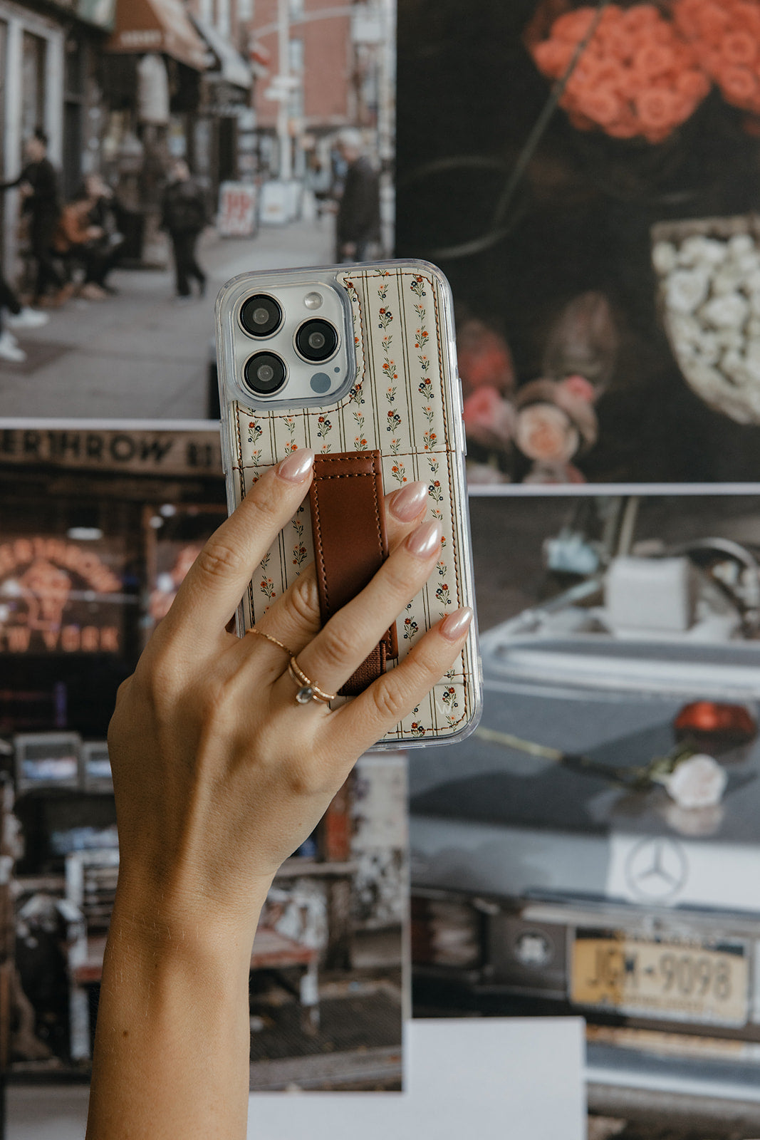 Hand holding floral clear phone case with brown leather-style strap