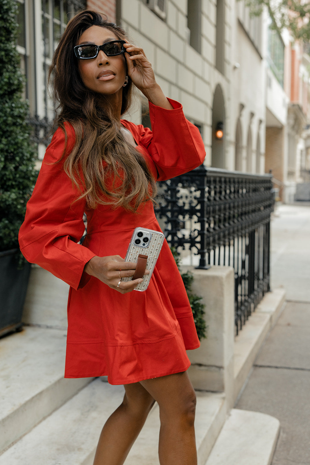 Floral phone case with brown strap, held by a model