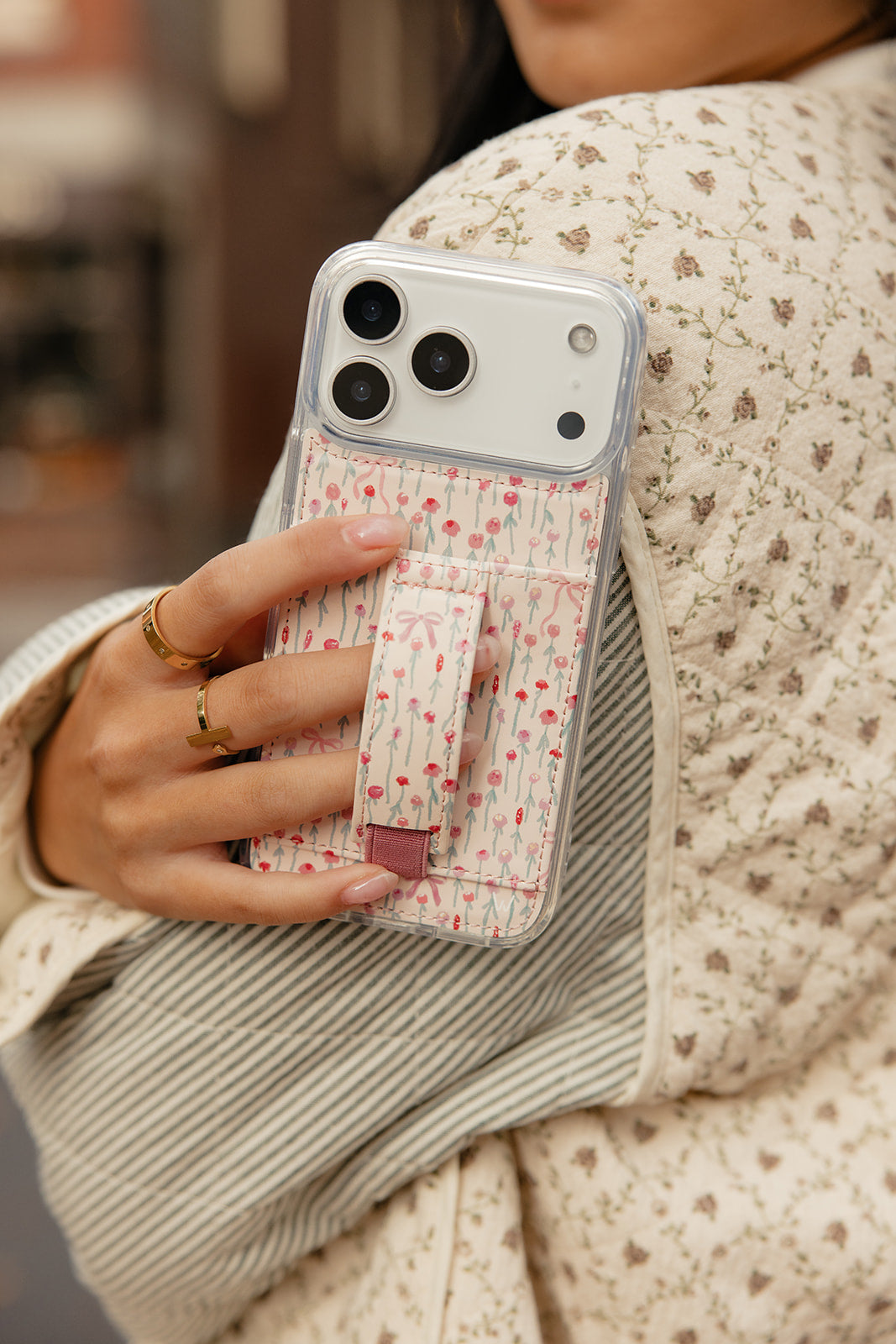 Pastel rose garden phone case with clear sides, pink floral pattern, and dangling strap