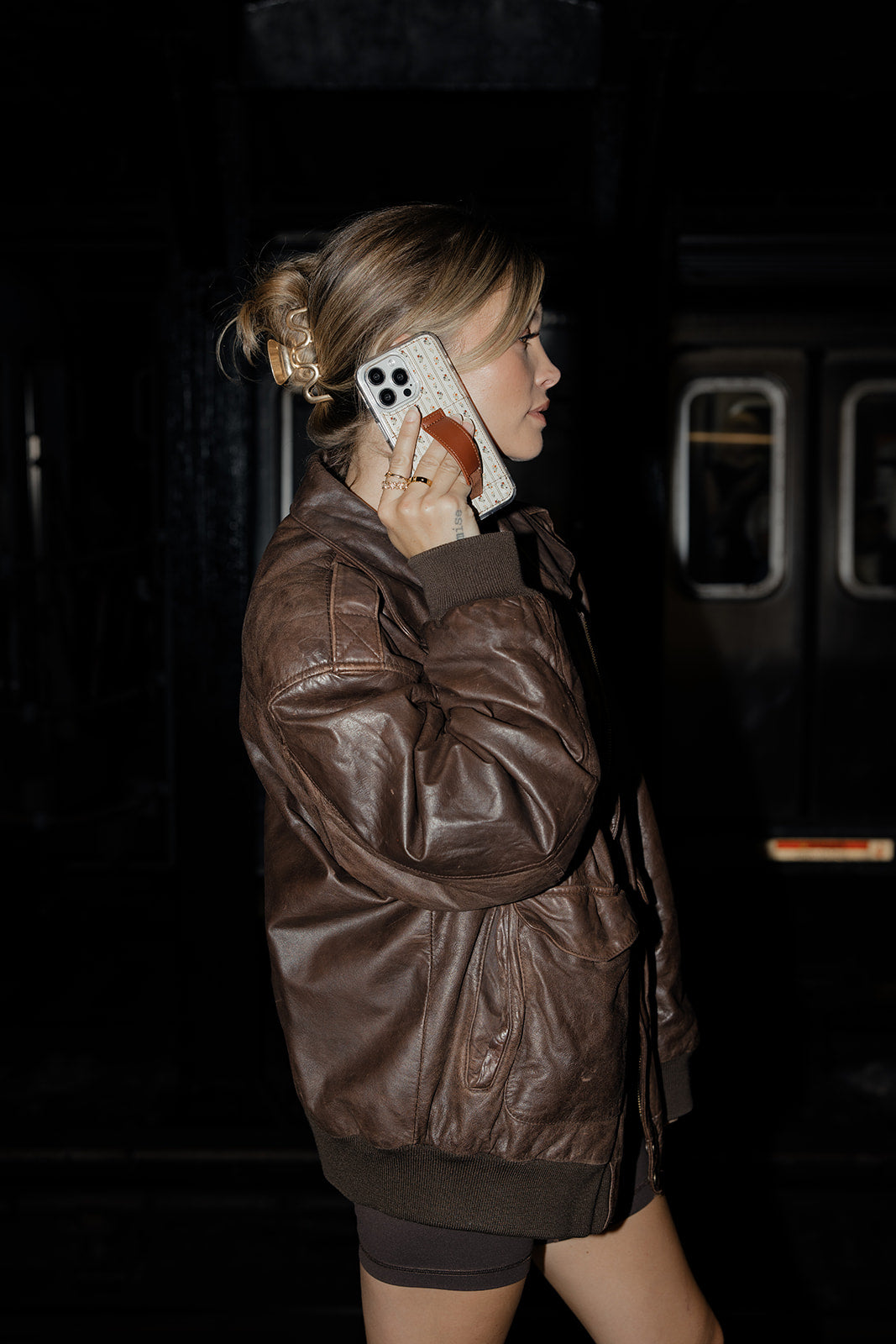 Floral clear phone case with brown leather-style strap, shown from the side