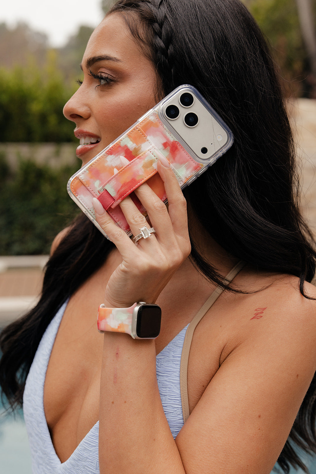 Watercolor orange and pink phone case with card pocket and wrist strap held up