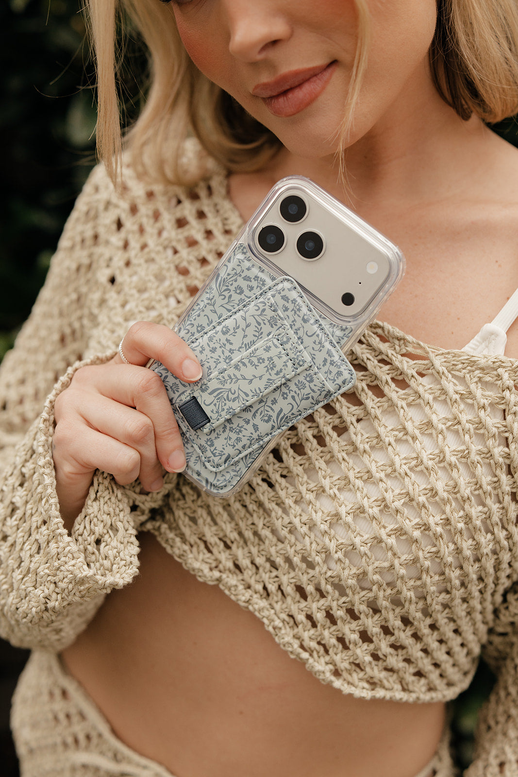 Magnetic phone case in light blue botanical floral print, held in hand.