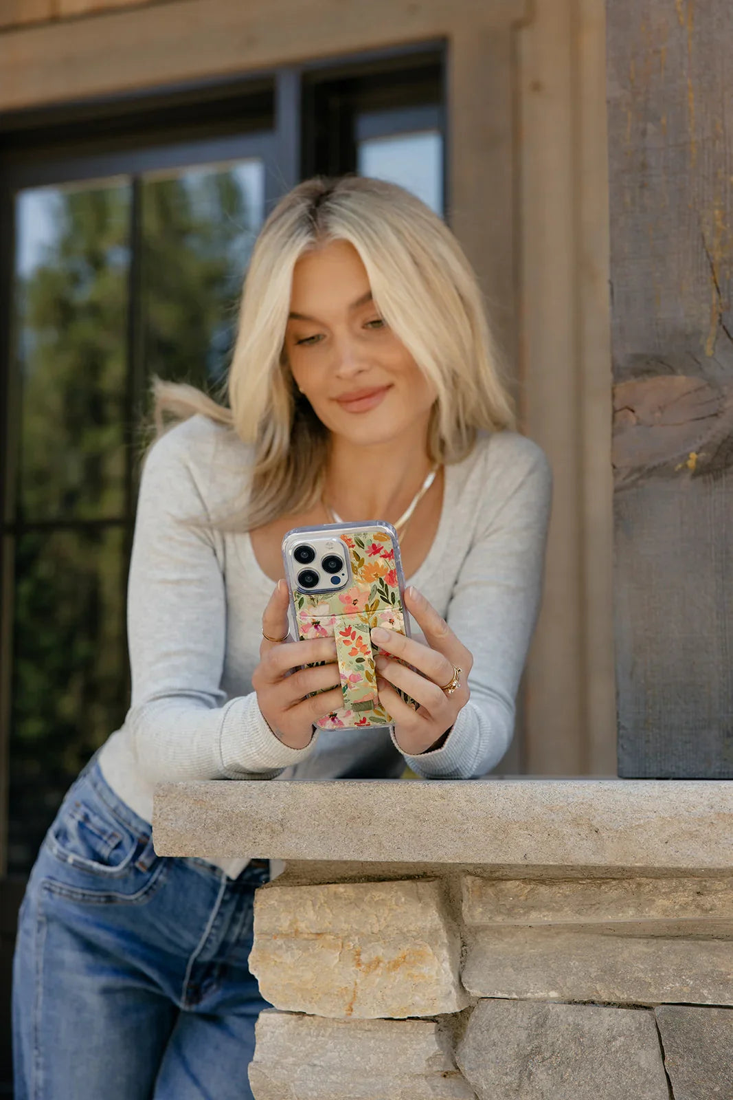 Floral clear phone case with green strap detail held in front of the chest.