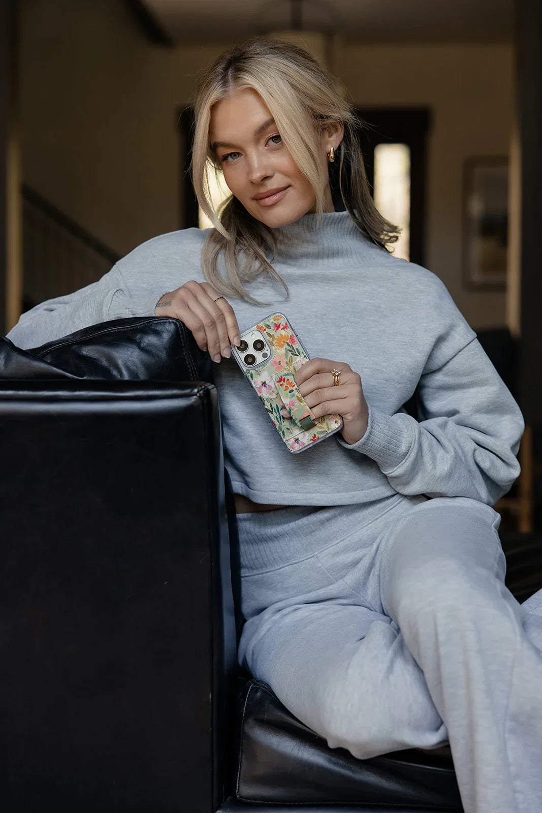 Floral phone case with clear edges and green strap detail held near the chest.