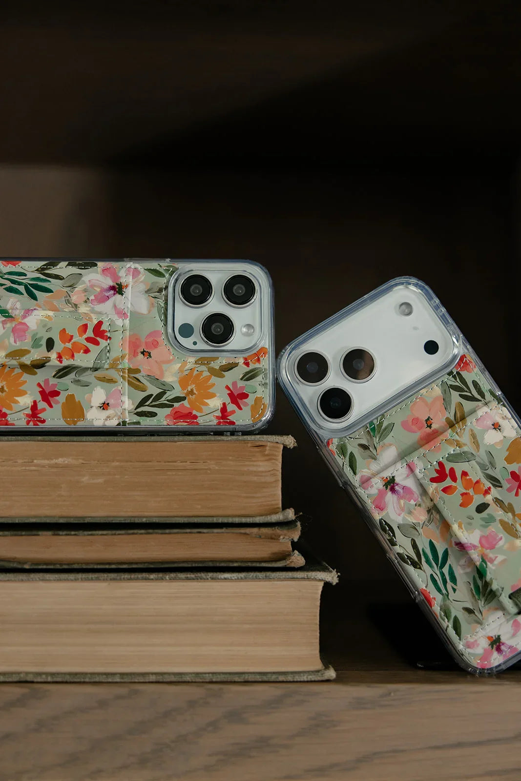 Floral phone cases with clear backs and green strap across the floral panel.